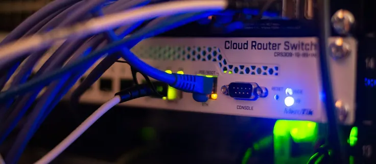Network cables gathered in a rack, in low light.