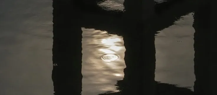 Pilares reflejados en agua oscura: la misma forma repetida al revés.